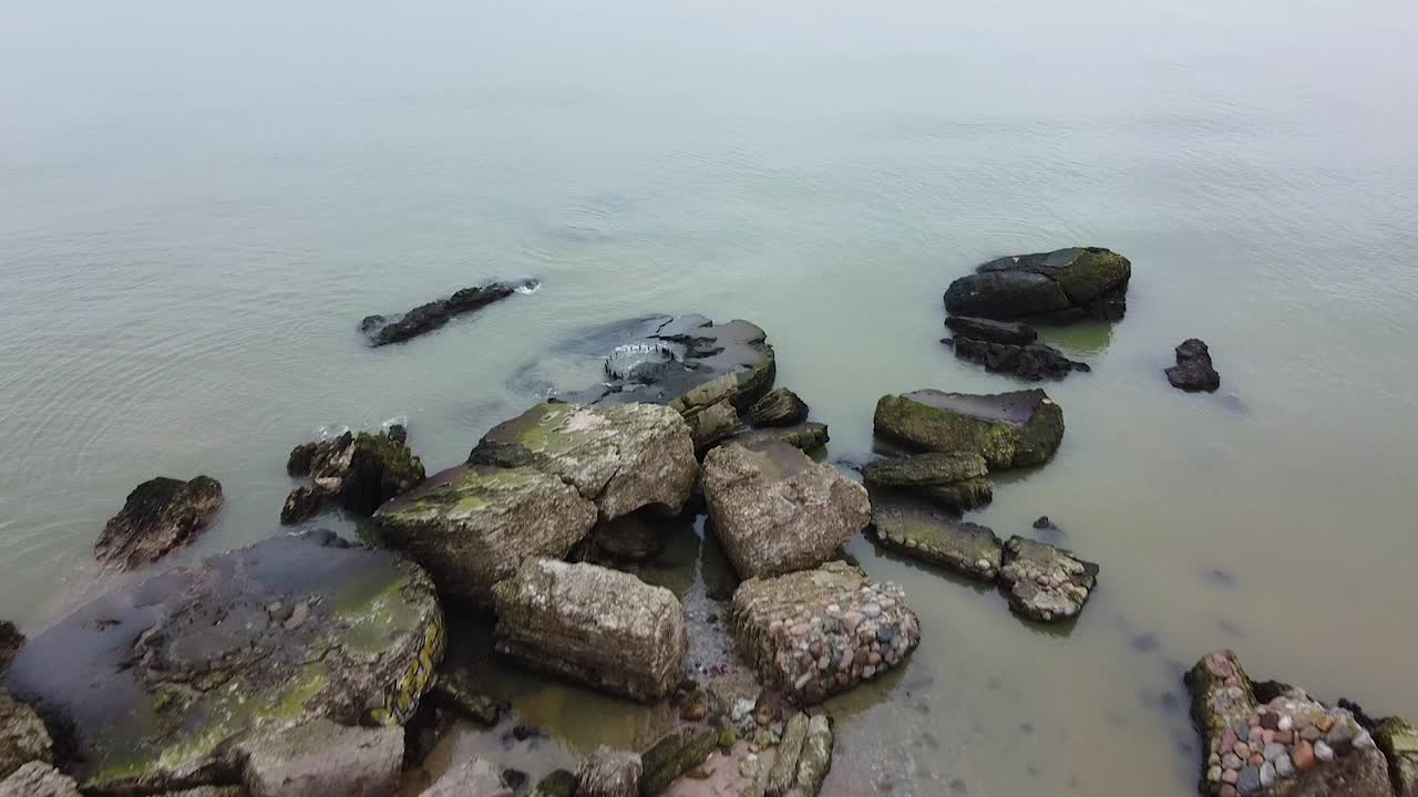 Vista aerea di un edificio di fortificazione costiera abbandonato presso i Forti Settentrionali di Karosta sulla spiaggia del Mar Baltico a Liepaja in una giornata primaverile nuvolosa, ampia ripresa con drone che si muove in avanti e rivela, con la telecamera che si inclina verso l'alto