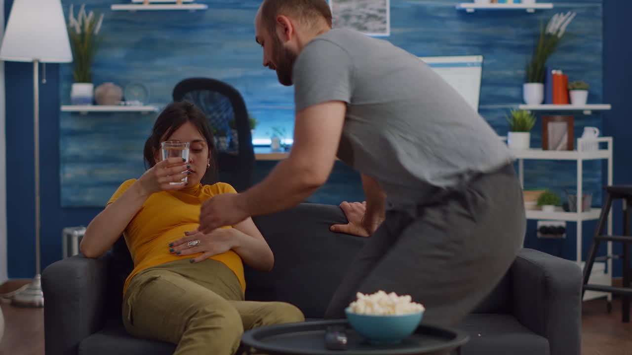 Young couple with pregnancy preparing for movie