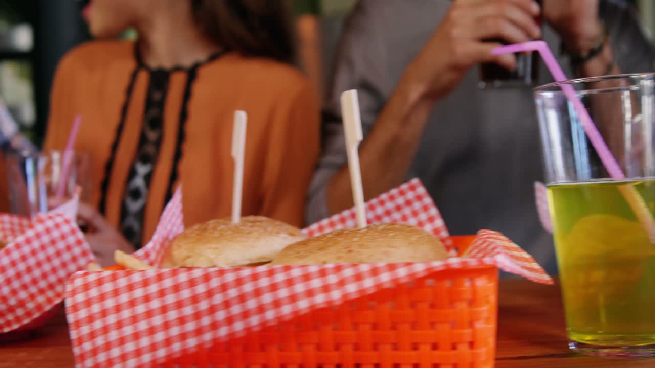 Amici che gustano hamburger e bevande al ristorante