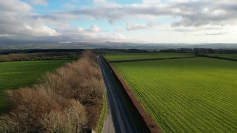 Aerial static shot of Cornwall's countryside with fields, road, and hills.