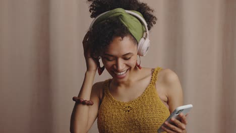 young african american lady in headphones choosing music on mobile app and dancing, recording video for social media