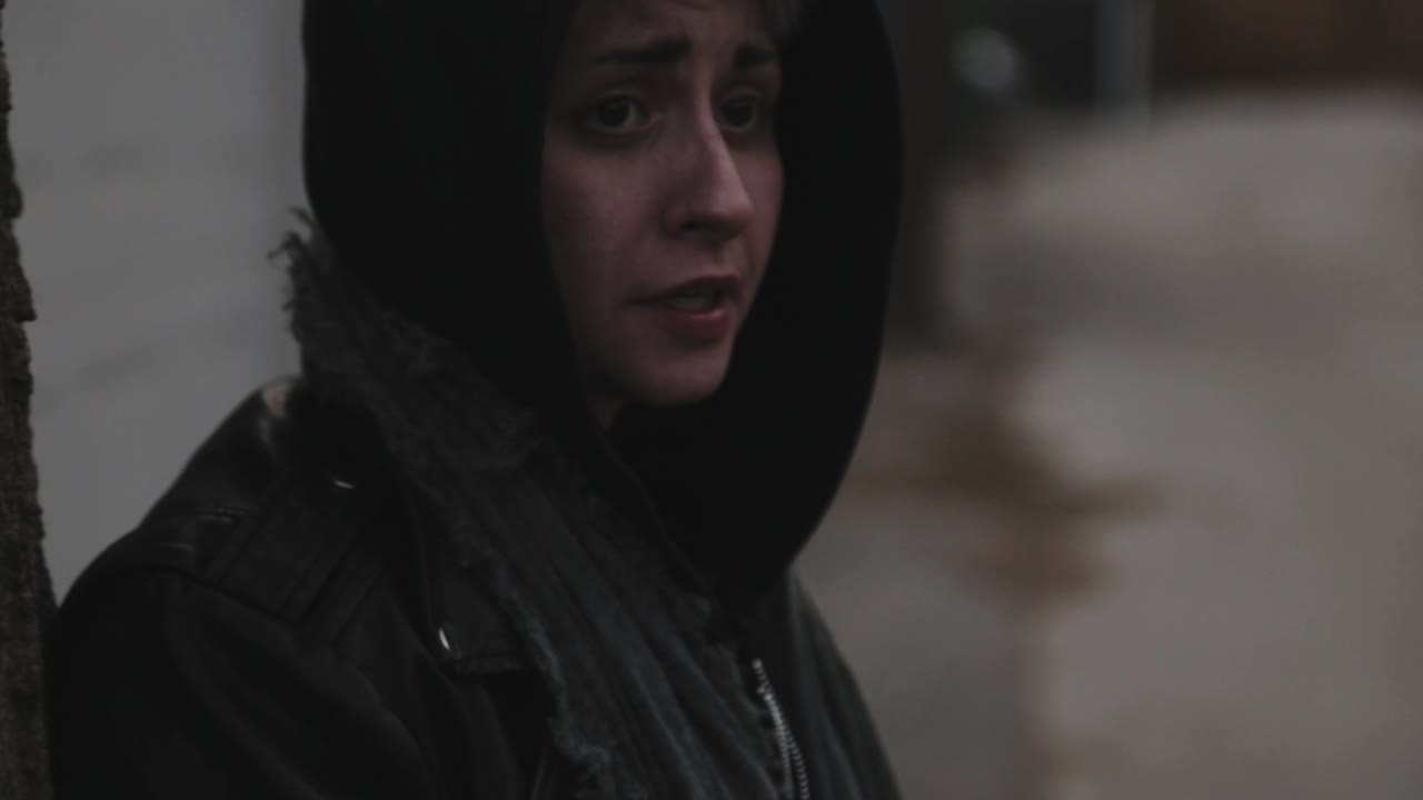 una persona triste se apoya contra un árbol