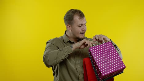 hombre alegre mostrando la inscripción de black friday de las bolsas de compras, sonriendo satisfecho con los precios bajos