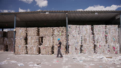 trabajador cuenta las balas apiladas de papel de basura almacenadas bajo el refugio, disparo de seguimiento