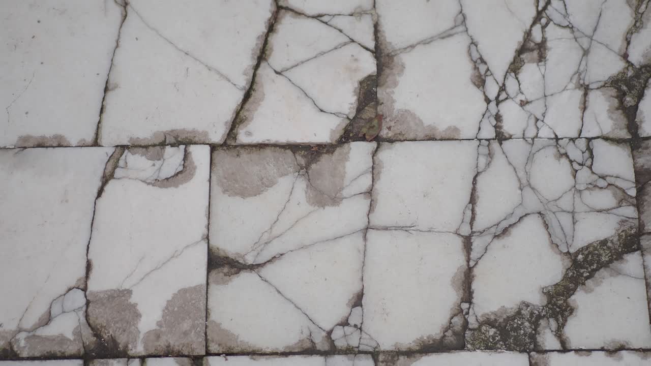 Close-up of Cracked and Stained White Floor Tiles