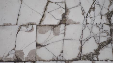 close-up of cracked and stained white floor tiles