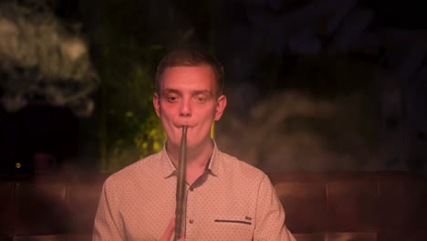 man smoking hookah in a nightclub