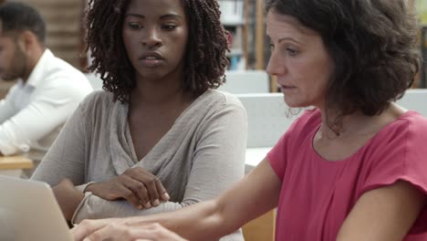 Mujeres-Concentradas-Usando-Laptop-En-La-Biblioteca