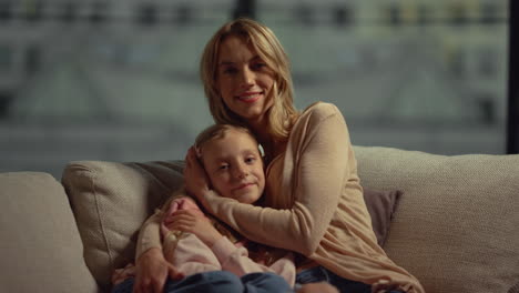 happy mother and daughter hugging on sofa