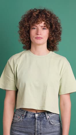 adult woman with curly hair looking unhappy showing thumbs down gesture. vertical orientation