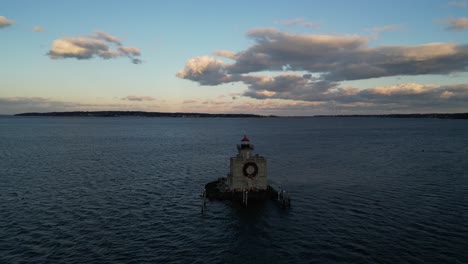 An-aerial-view-of-the-Huntington-Harbor-Lighthouse-on-Long-Island,-NY-at-sunset,-with-a-Christmas-wreath