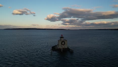 una vista aérea del faro del puerto de huntington en long island, nueva york al atardecer, con una corona de navidad