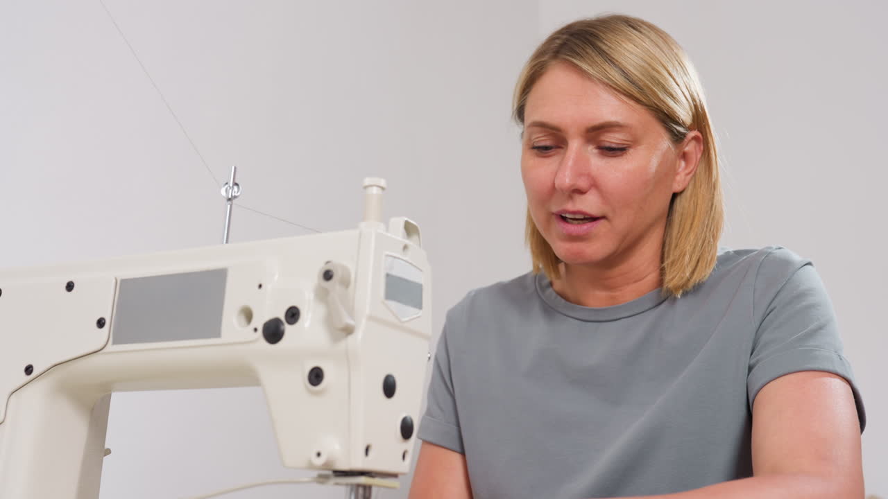 Female couturier with bright face, eyes focused on electric sewing machine, discussing design ideas with colleague, demonstrating technique, ensuring garment perfection, radiating concentration