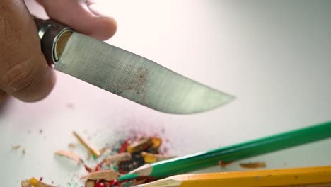 Footage-of-hands-slowly-sharpening-a-pencil-and-some-coloured-pencils-with-a-sharp-knife