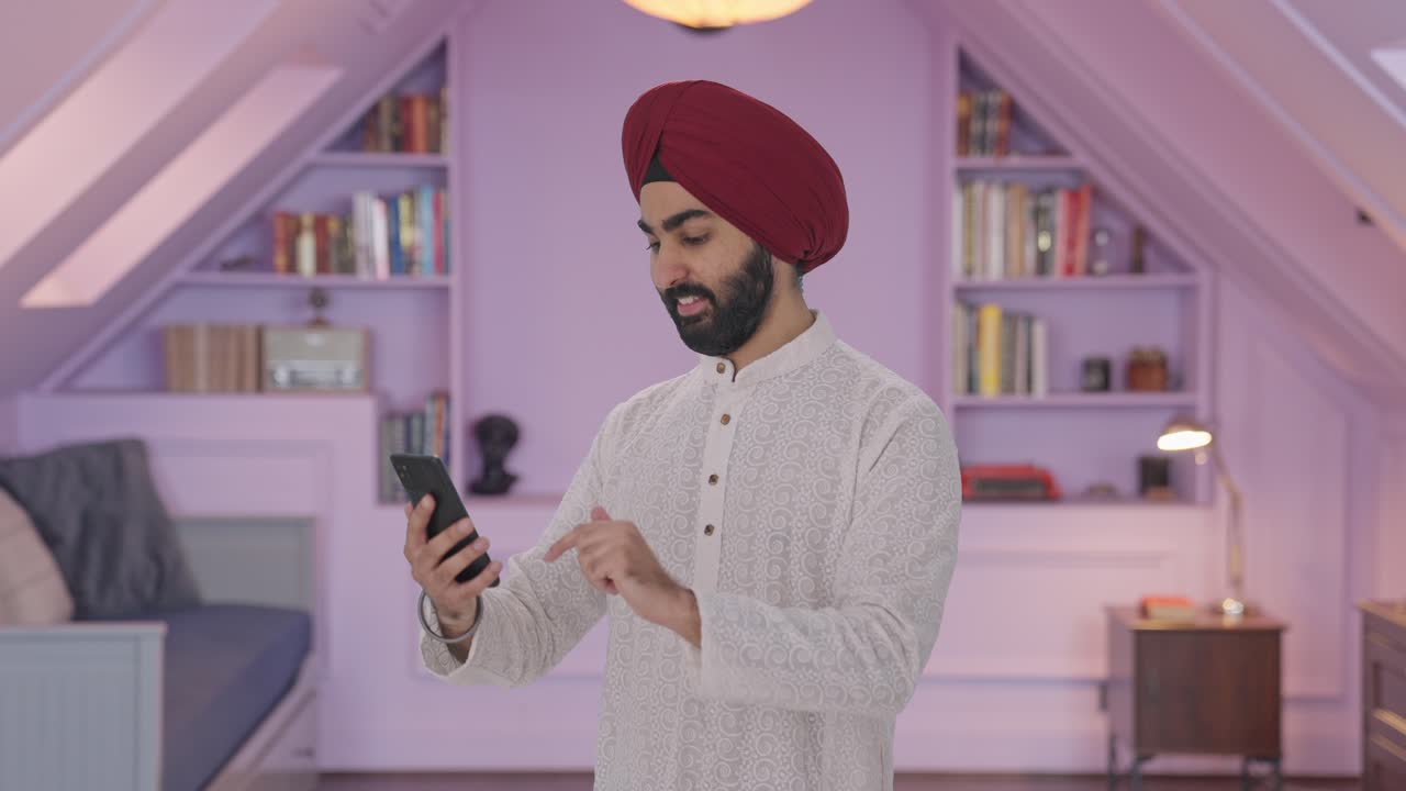 Uomo indiano Sikh felice che usa il telefono