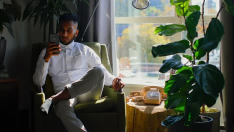 Front-view-of-young-asian-man-using-mobile-phone-in-living-room-at-home-4k