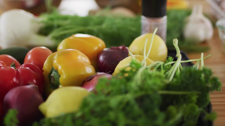 Lots of vegetables, cooking ingriedients and spices lying on a kitchen table