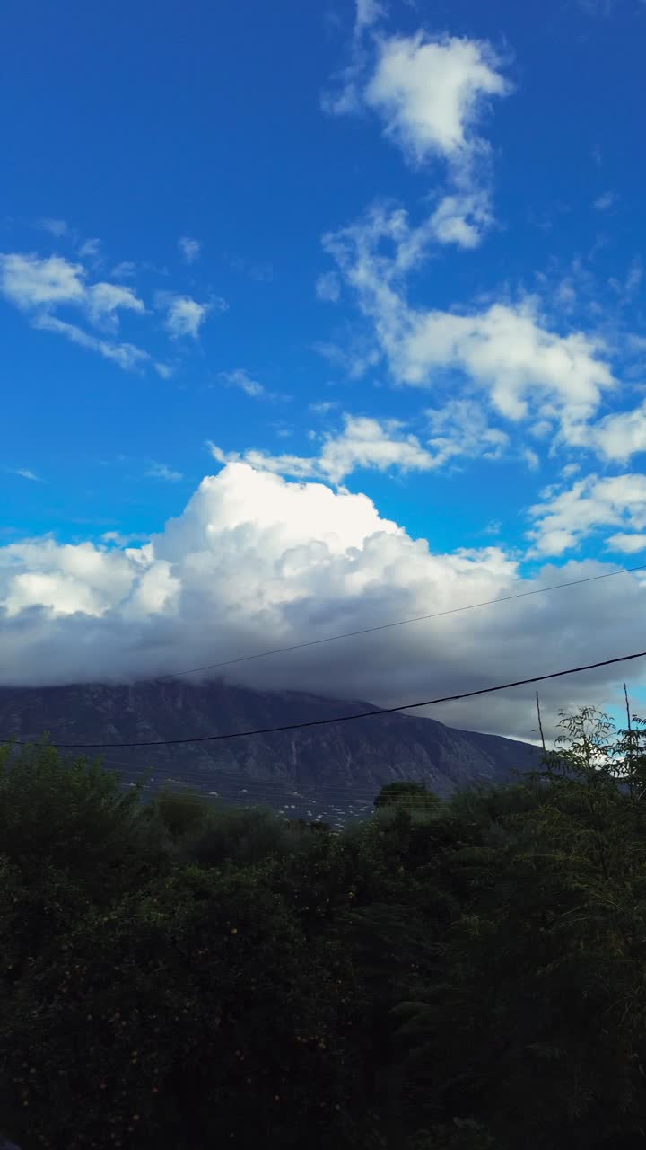 Aerial, low altitude view of Taygetos mountain located at Messinia, Peloponnese, Greece covers with beautiful clouds on an autumn day, footage taken from Kalamata, left pan 4k vertical
