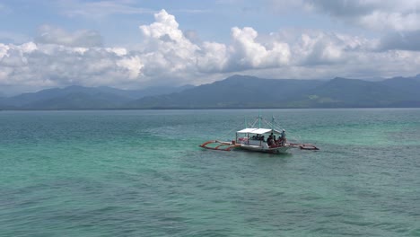 barco con turistas navegando en el océano azul y llegando al resort dos palmas island en puerto princesa, palawan, filipinas