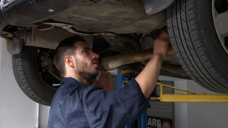 Hübscher-Mechaniker,-Der-Ein-Auto-überholt,-Während-Er-Telefoniert