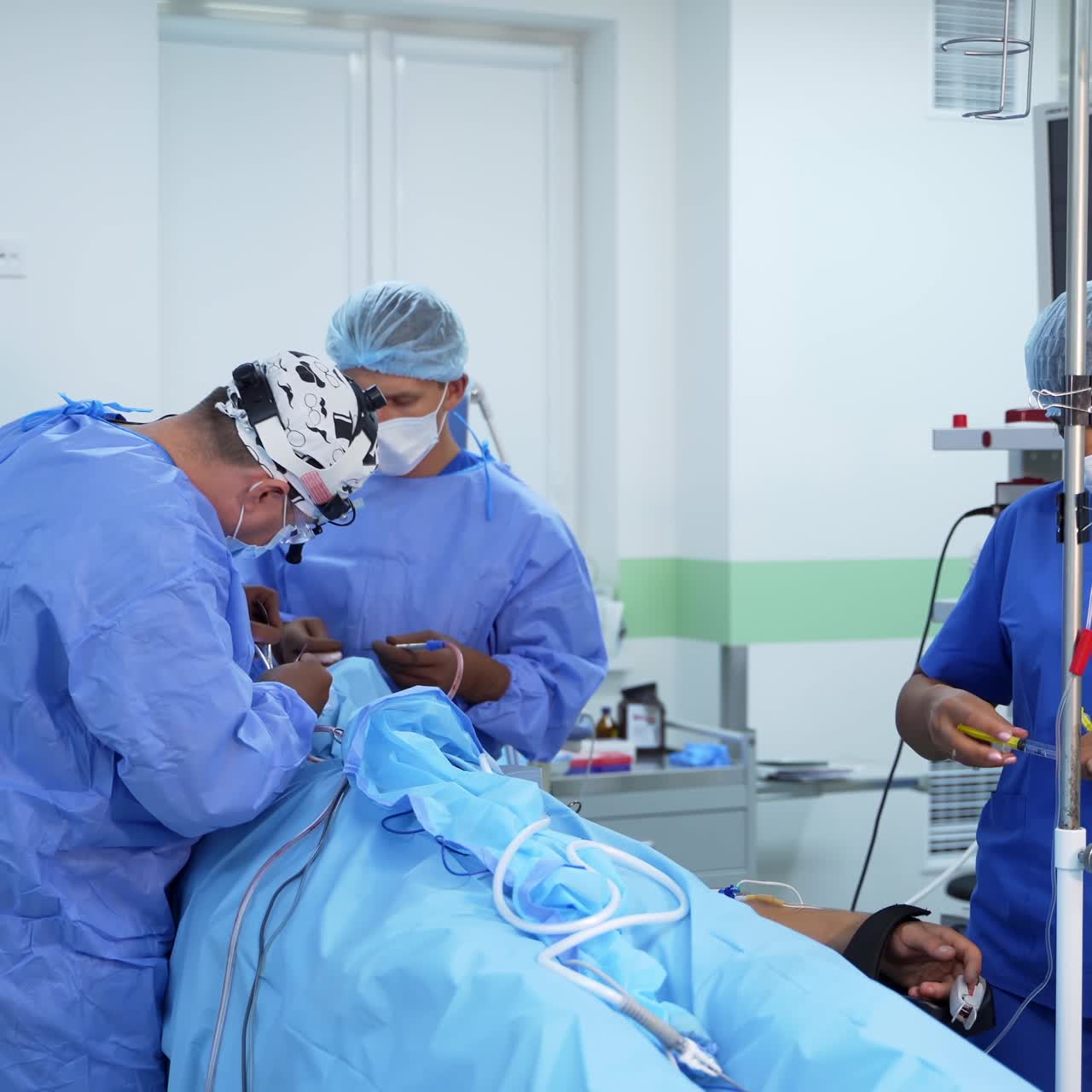 Team of surgeons in operating room. Surgical process on the background of modern equipment in clinic. Doctors in uniform use medical devices