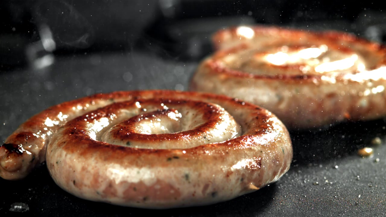 Salsicce a spirale sfrigolanti che friggono in una padella calda