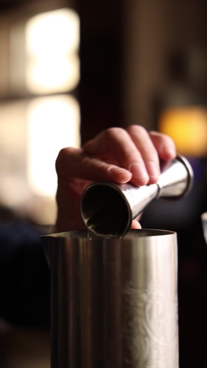 Barman che versa alcol in un misurino e uno shaker da cocktail