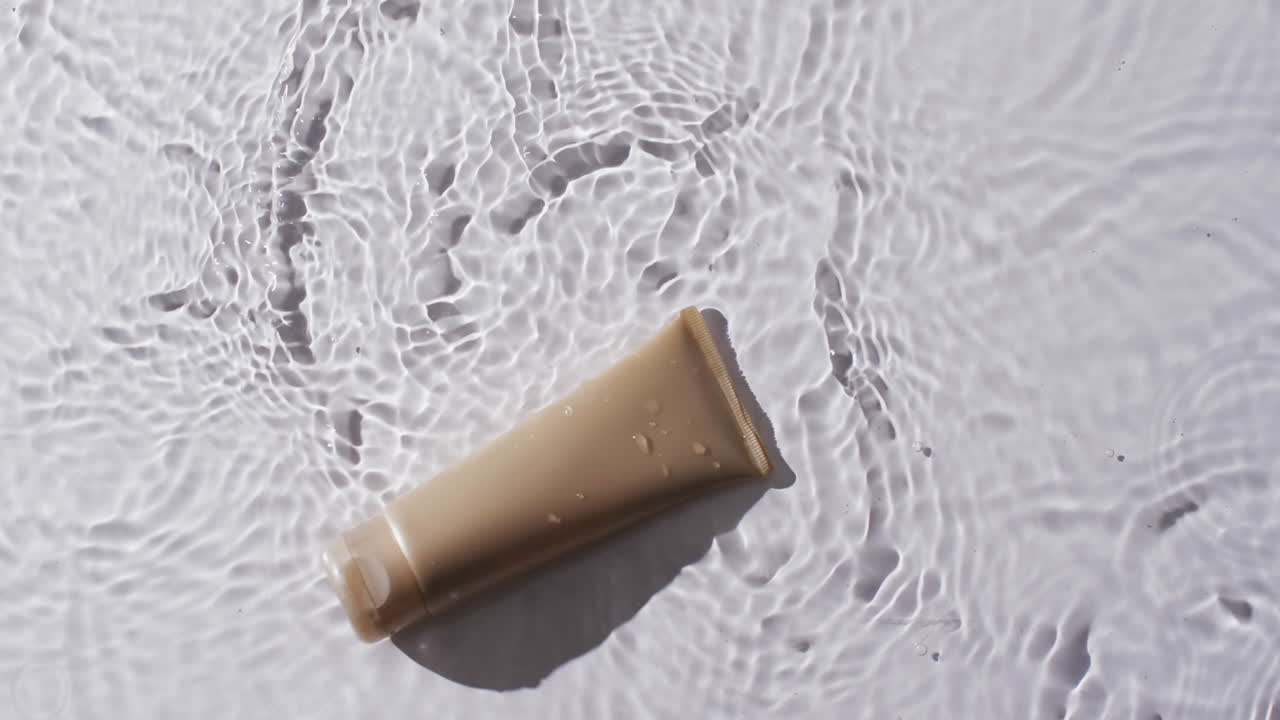 색 배경에 복사 공간과 함께 물에 있는 미용 제품 튜브의 비디오