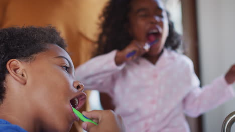 Padre-Ayudando-A-Los-Niños-A-Cepillarse-Los-Dientes-En-El-Baño-De-Casa