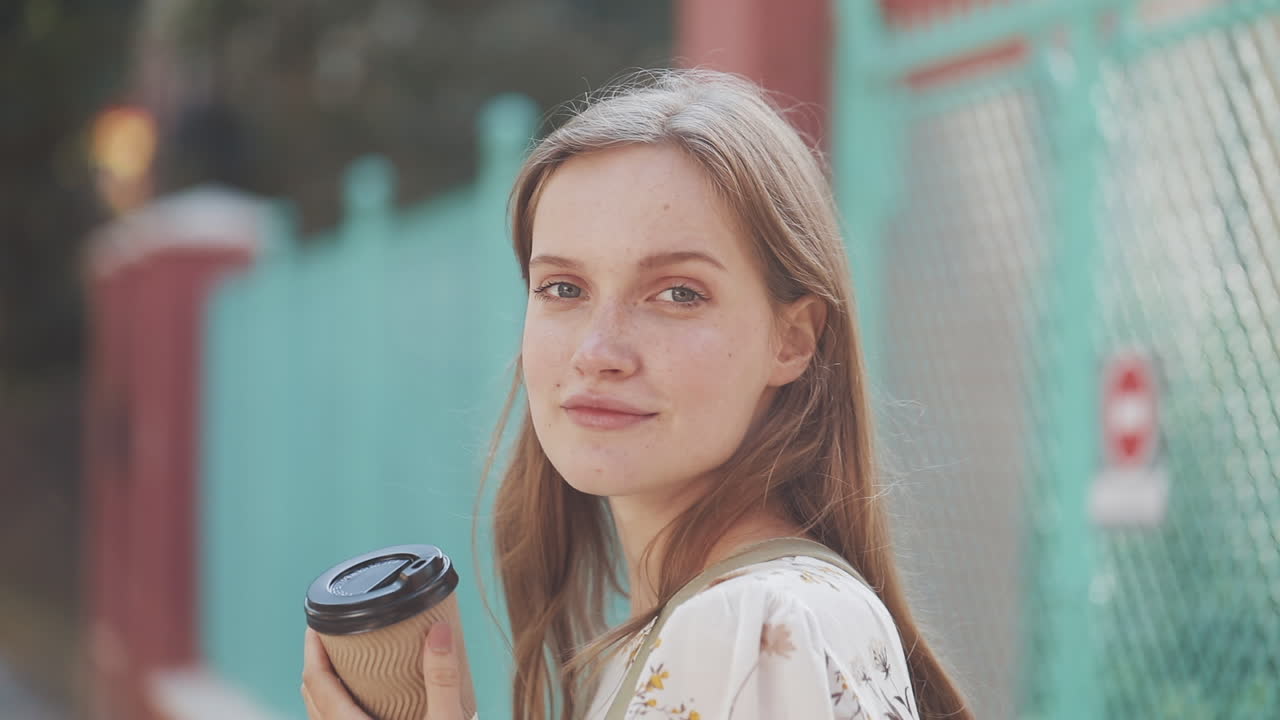 街の路上でコーヒーを飲む若い女性。