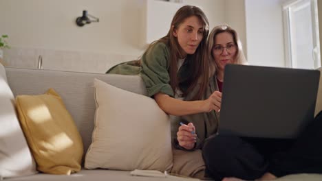dos mujeres trabajando juntas en una computadora portátil en casa