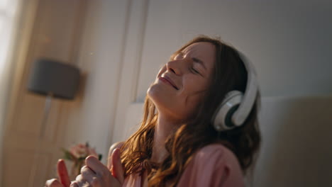 carefree girl enjoying earphones sound at home closeup. energetic female listen