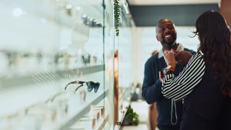 a man and woman looking at glasses in an optician's store.