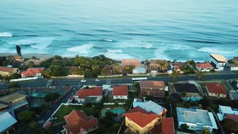 aerial view taken with a drone flying over residential homes with a view of the sea in the distance