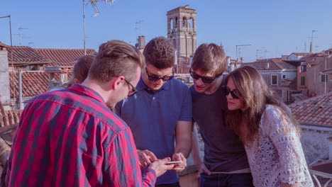 friends looking at a phone on a rooftop in venice