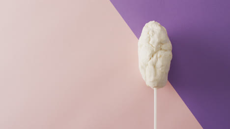 video of marshmallow on stick lying on pink and violet surface