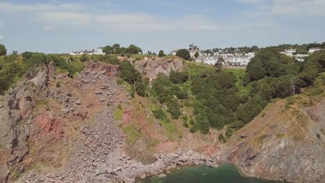 Aerial-shot-heading-towards-giant-Cliffside,-overlooking-a-small-town