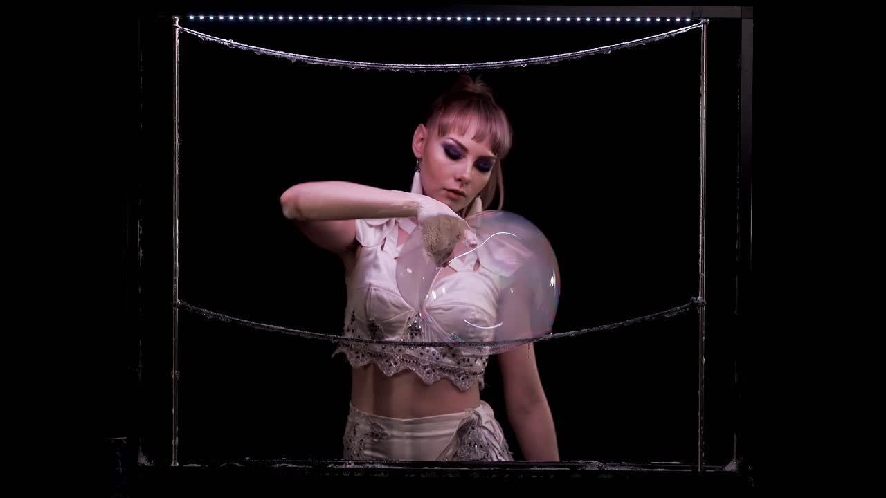 소녀는 비누 거품으로 트릭을 합니다. 그녀는 한 거품을  ⁇ 고 연기가 이웃으로 흘러들어갑니다.