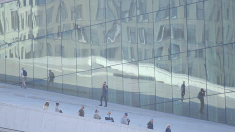 visitors explore around oslo opera house with contemporary architecture, norway