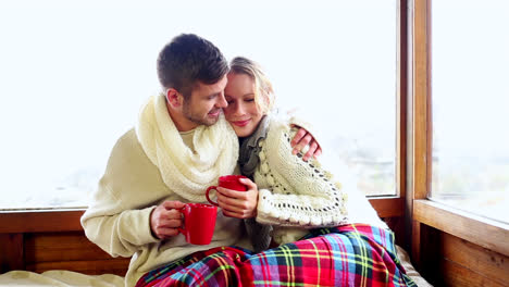 cute couple relaxing together under a blanket in their ski lodge