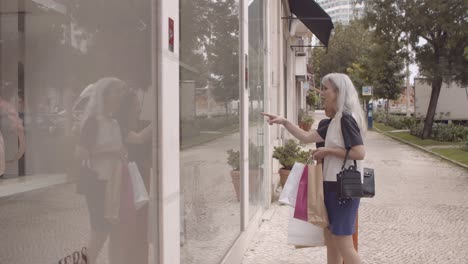 dos damas con bolsas de compras caminando por tiendas de moda