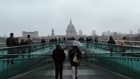 rainy day on millennium bridge, london with st. paul's cathedral in the background