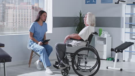 enfermera consultando con un paciente en silla de ruedas