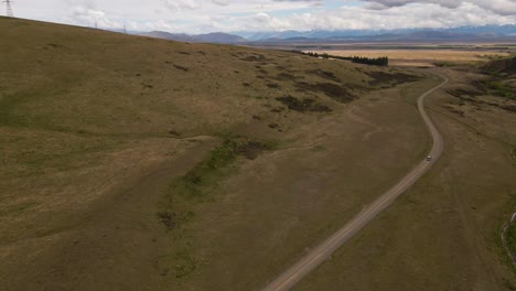 Car-traveling-along-road-in-rural-Canterbury,-New-Zealand