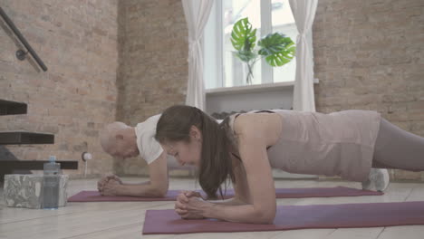 vieille femme et homme sur un tapis de yoga à la maison