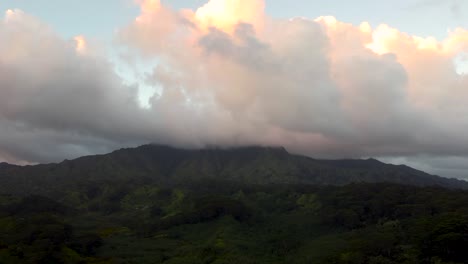 Dramatic-aerial-flyover-revealing-lush-green-rainforest,-rivers,-mountains-and-streams-during-sunset-with-yellow-clouds