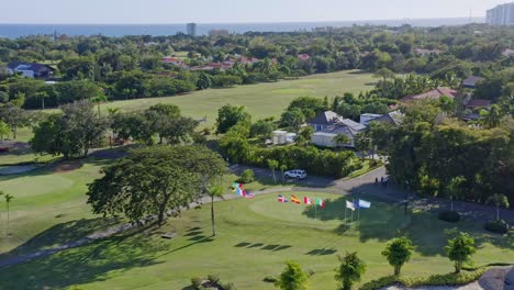 Vista-Aérea-Del-Campo-De-Golf-Y-Diferentes-Banderas-En-El-Club-De-Campo-Metro,-Juan-Dolio,-República-Dominicana---Disparo-De-Drones