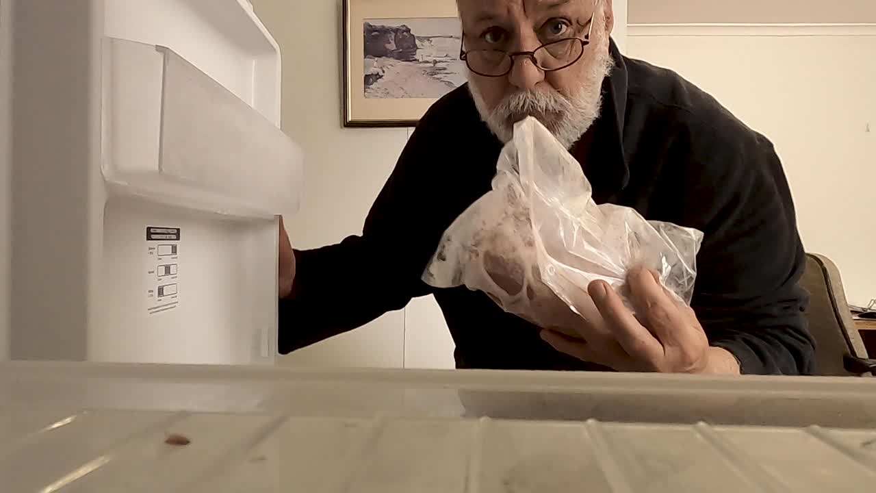 hombre con cuentas abriendo la puerta del refrigerador y recuperando comida