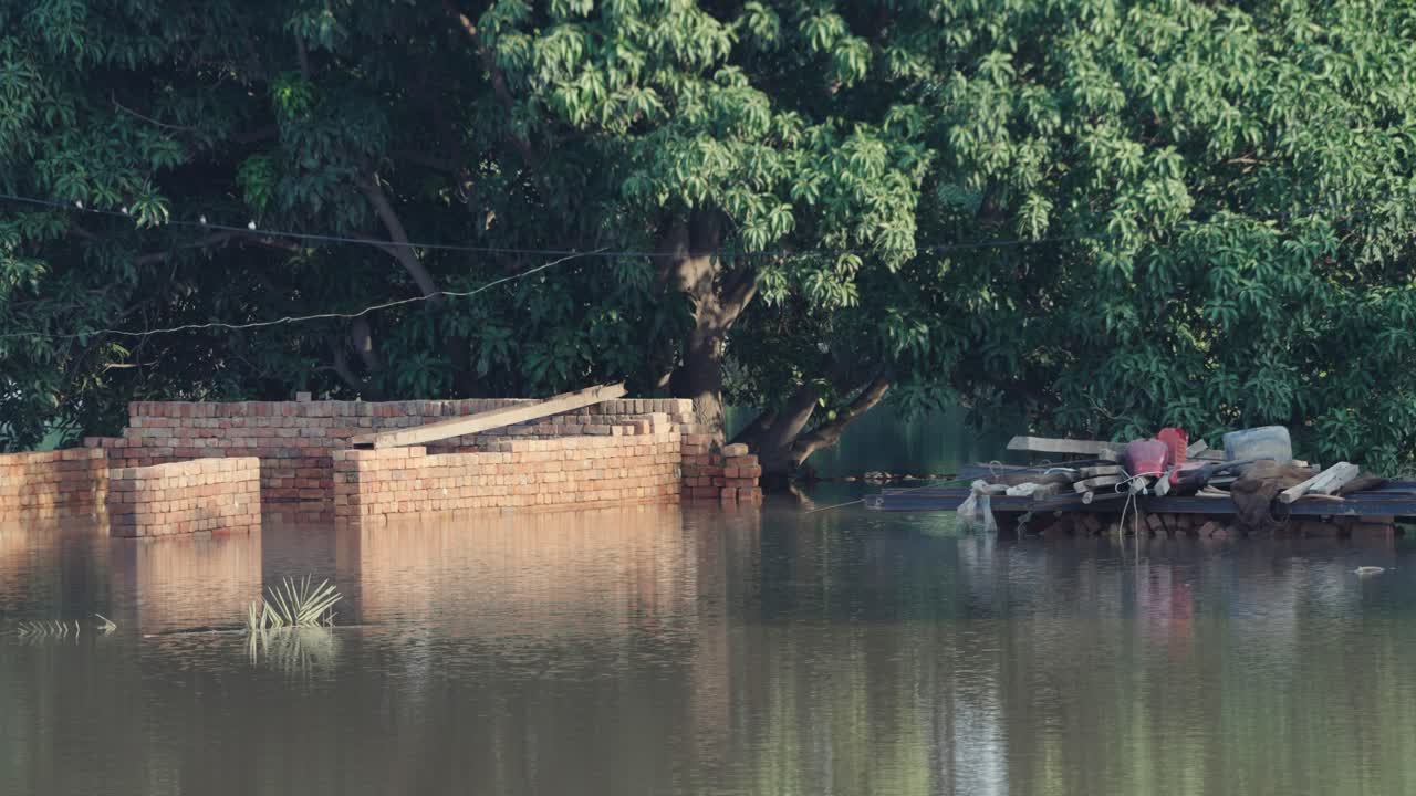 paredes de ladrillo y pertenencias parcialmente sumergidas en agua de inundación, Jalalpur Pirwala, Punyab, Pakistán