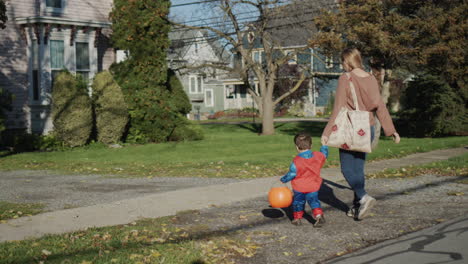 parent leads by the hand a little boy in a costume, they go for candy on halloween